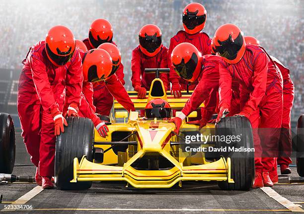 pit crew team pushing open-wheel single-seater racing car racecar - pit stock-fotos und bilder