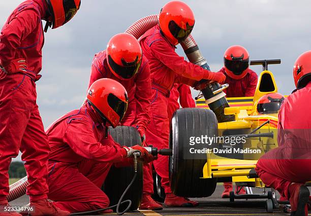 pit crew changing tire on formula one racecar - car racing stock-fotos und bilder