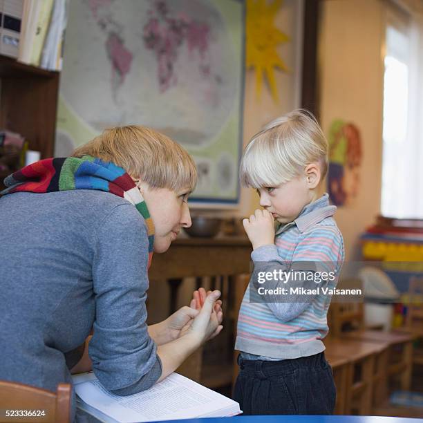 teacher comforting sad boy in classroom - sad kid in kindergarten stock pictures, royalty-free photos & images