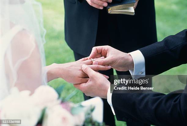 bride and groom exchanging rings - wedding rings stock-fotos und bilder