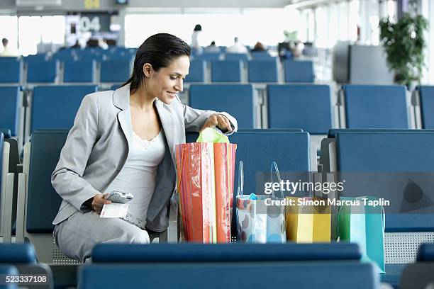 woman waiting in airport with shopping bags - airport shopping stock-fotos und bilder