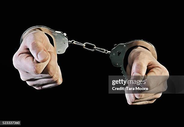 hands in handcuffs - handcuffs photos et images de collection