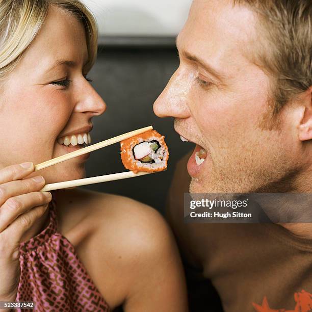 woman feeding man sushi - hugh sitton stockfoto's en -beelden