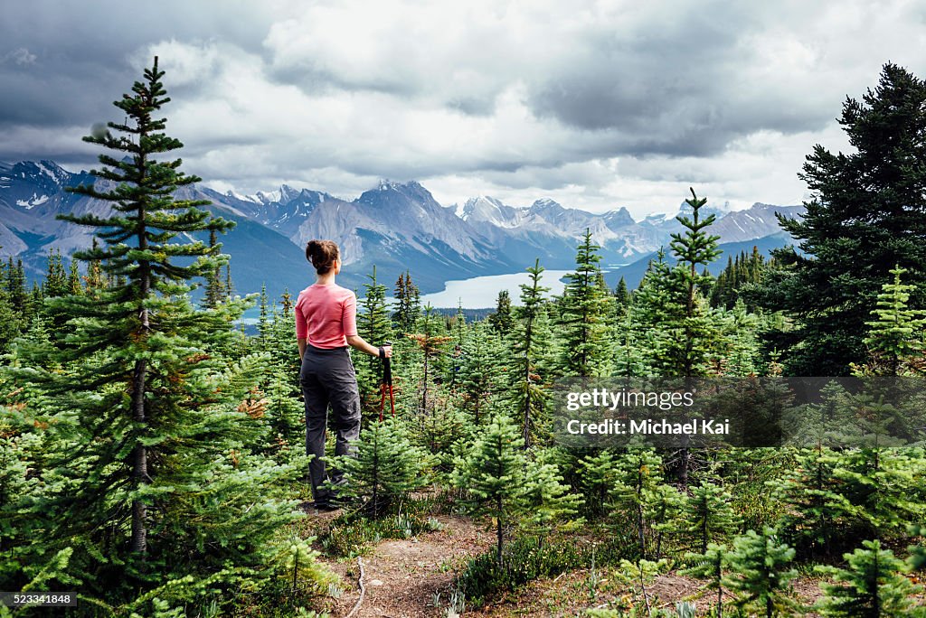 Young woman hiking through pine trees along Maligne Lake, Alberta, Canada