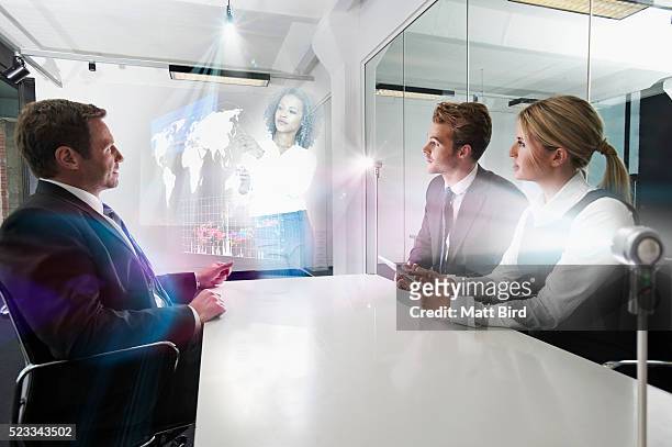 people in meeting watching holographic presentation - hologramm stock-fotos und bilder