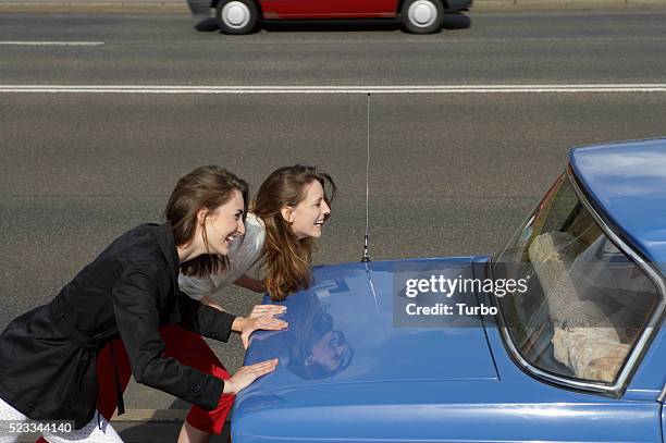 two young women pushing broken car - car profile stock pictures, royalty-free photos & images