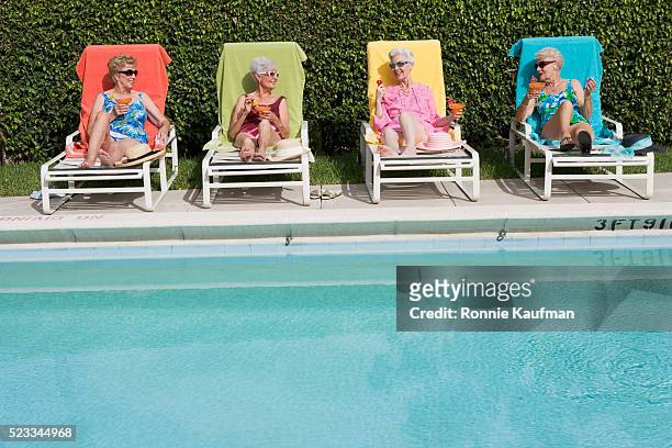 senior friends poolside with drinks - women sunbathing pool - fotografias e filmes do acervo