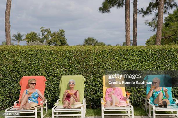 senior friends sunbathing with drinks - 4 cocktails stockfoto's en -beelden