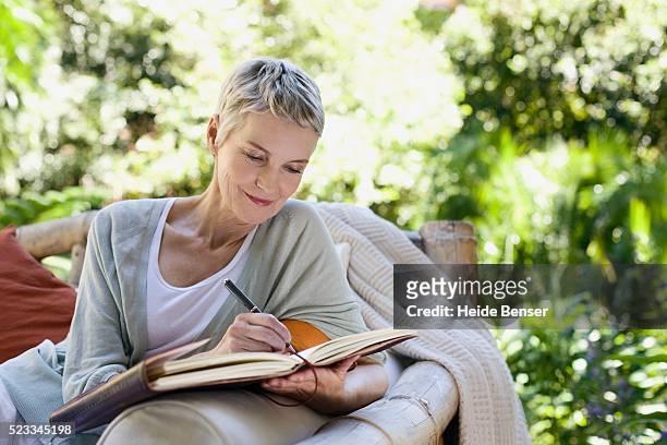 woman writing in a journal - terugkijken stockfoto's en -beelden