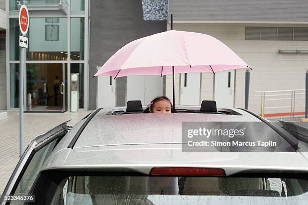 little girl peeking from sunroof on rainy day - regen auto stock-fotos und bilder