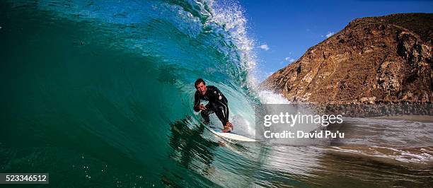 surfer riding through tube wave - surf tube stock-fotos und bilder