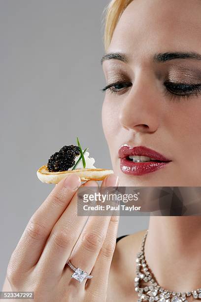 woman holding a canape with caviar topping - fish roe stock pictures, royalty-free photos & images