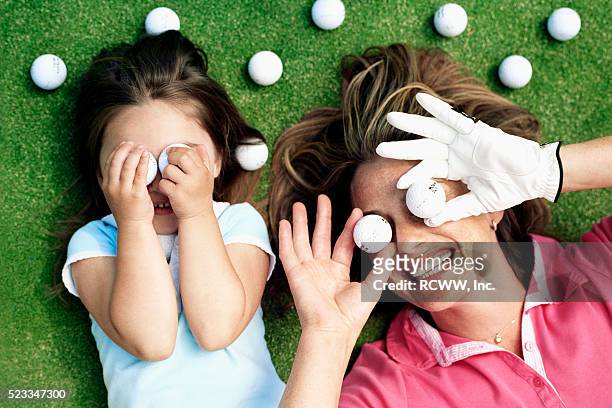 mother and daughter playing with golf balls - golf girls stock-fotos und bilder