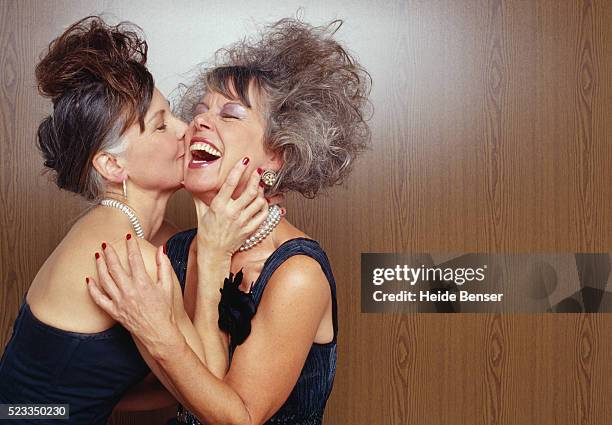 two mature women wearing evening dresses - friends kissing cheeks fotografías e imágenes de stock