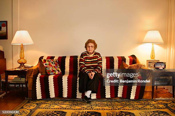 senior woman sitting on a sofa - old woman sitting stock-fotos und bilder