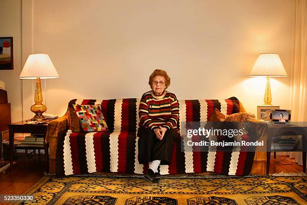senior woman sitting on a sofa - senior loneliness stock pictures, royalty-free photos & images