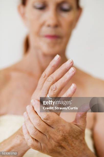 woman holding her hand - arthritis hands photos et images de collection