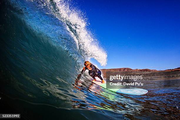 a teenage girl ducks to get past the lip as she races the tube to make this wave - surf tube stock pictures, royalty-free photos & images