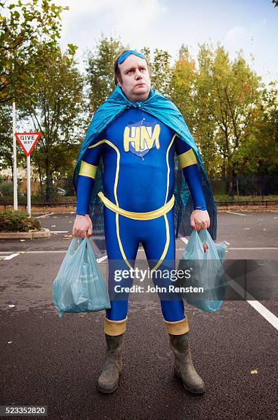 overweight man dressed as hero holding shopping bags - chubby man shopping stock-fotos und bilder