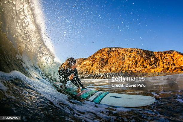 teenage girl (16-17) riding longboard through water tube on maibu coast, california, usa - malibu foto e immagini stock