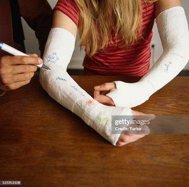 man signing cast on woman's arm - red colour cast stock pictures, royalty-free photos & images