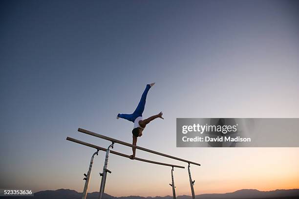 gymnast performing on parallel bars in the desert - brug turntoestel stockfoto's en -beelden