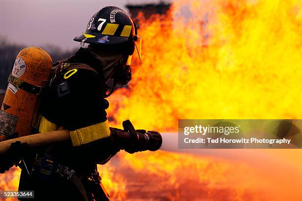 firefighter battling flame - firefighter fotografías e imágenes de stock