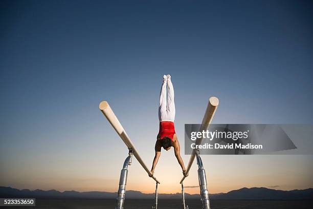 gymnast performing on parallel bars in the desert - barras paralelas barra de ginástica - fotografias e filmes do acervo