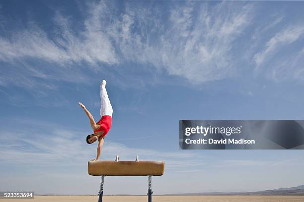 gymnast performing on pommel horse in the desert - gymnastics equipment stock pictures, royalty-free photos & images