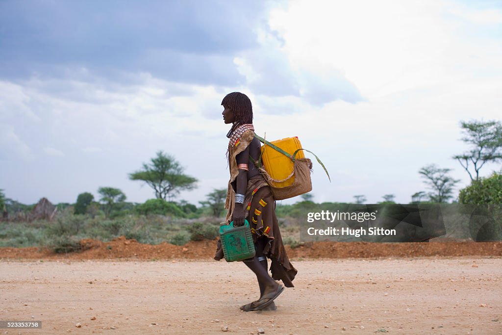 Hamer Woman Carrying Water Containers on Road