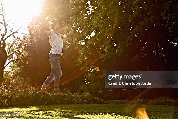 young woman slacklining in park on sunny day, north rhine-westphalia, germany - woman tightrope stock pictures, royalty-free photos & images