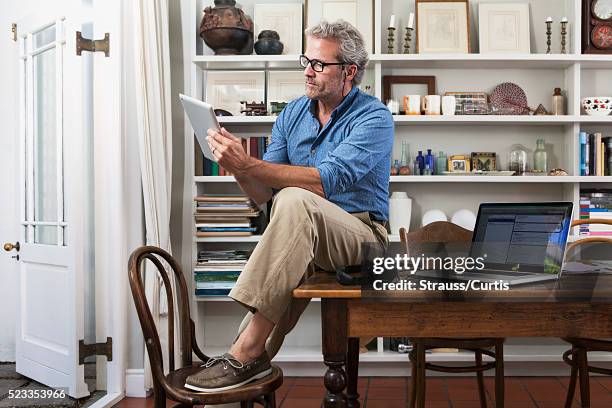 man seated on table holding tablet - internet banking stock pictures, royalty-free photos & images