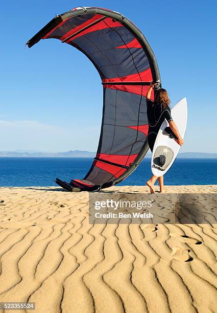 kite surfer carrying equipment - kite surf stock-fotos und bilder