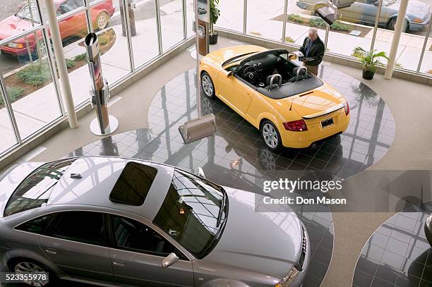 man looking at an audi convertible - show room photos et images de collection