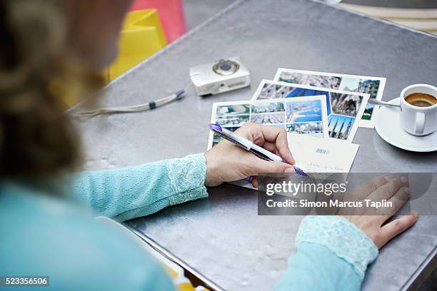 woman writing postcards on table - postkarte stock-fotos und bilder