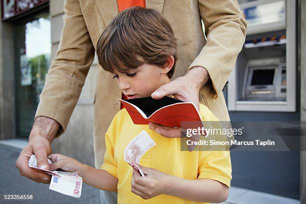 father and son putting money in wallet - putting money together stock pictures, royalty-free photos & images