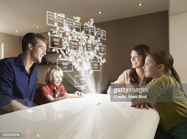 family looking at family tree on futuristic device - family history stock-fotos und bilder