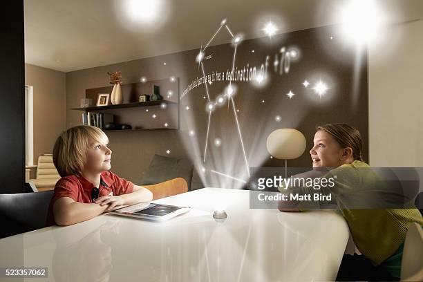 boy and girl looking at astronomical projection on futuristic device - astronomy bird stock-fotos und bilder