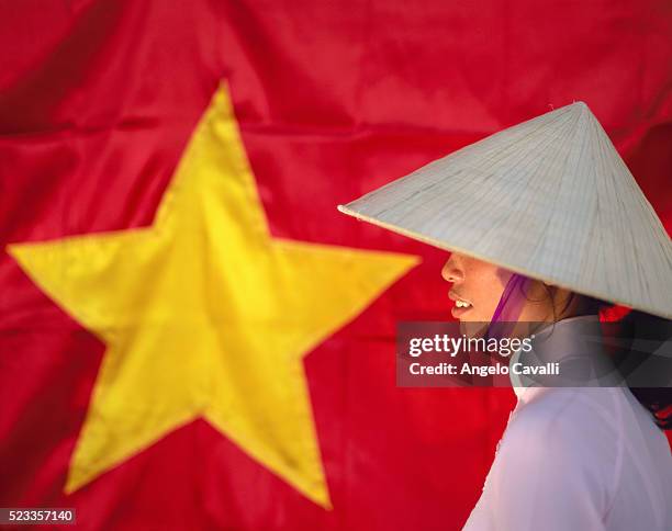 woman in conical hat alongside vietnamese flag - vietnam flag stock pictures, royalty-free photos & images