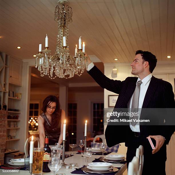 man lighting candles on chandelier - formal dining stock pictures, royalty-free photos & images