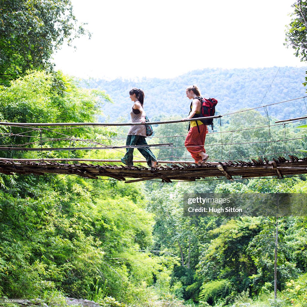 Two female tourists crossing hanging bridge