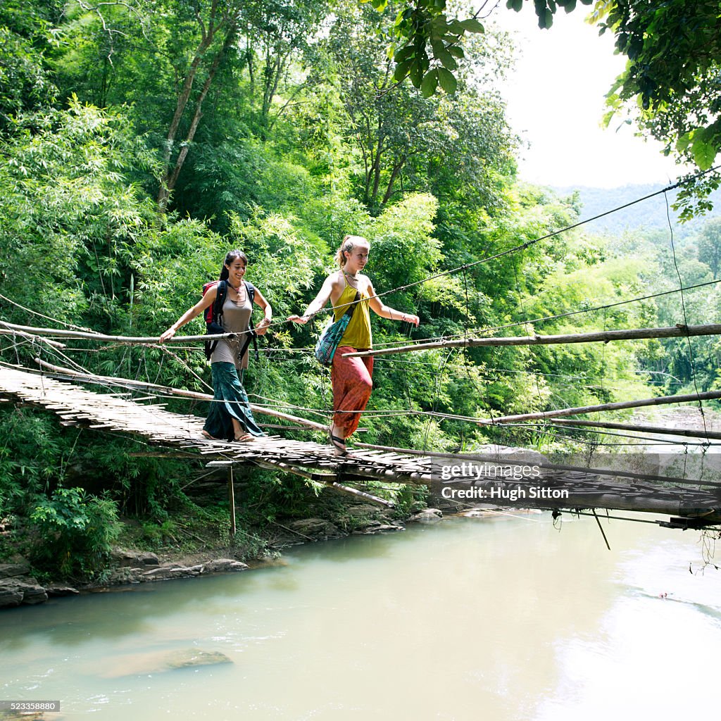 Two female tourists crossing hanging bridge