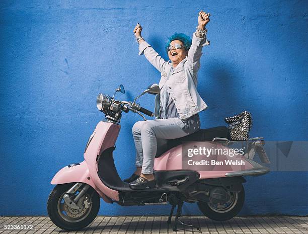 senior woman with blue hair on a motor bike. - moped stock-fotos und bilder