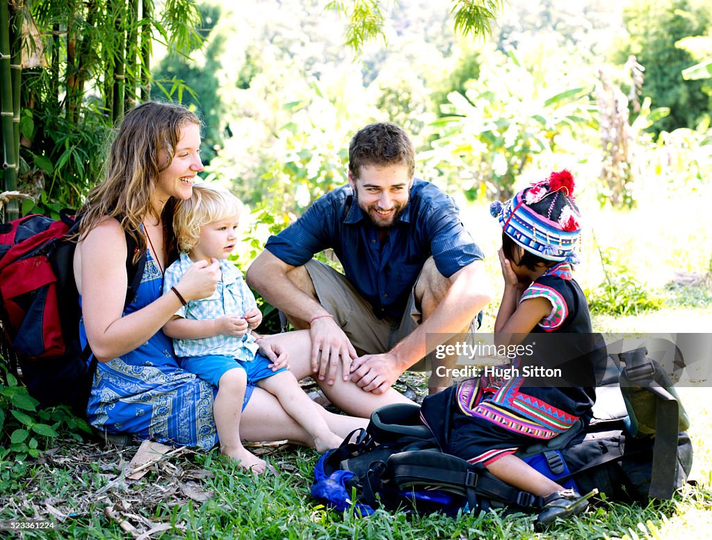 Young couple sitting with their son (12-23 months) and local child (4-5), Chiang Mai, Thailand