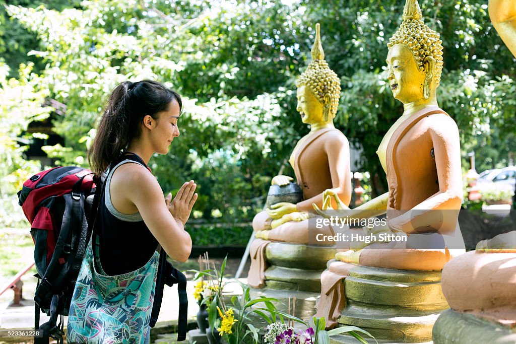 Female tourist praying with in front of Buddha sculptures, Chiang Mai, Thailand