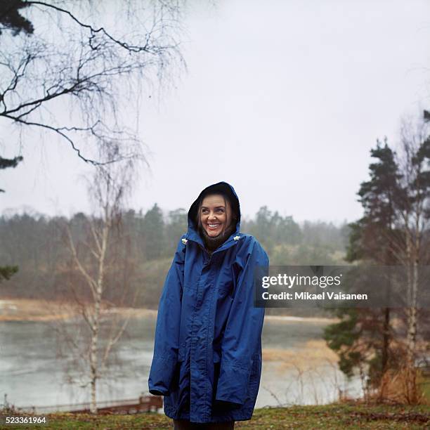 young woman standing in rain - レインコート ストックフォトと画像