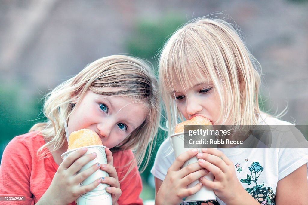 Two young girls (4-7) eating snow cones together