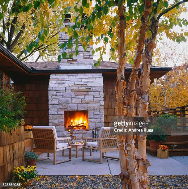 an outdoor fireplace and deck attached to a house finished with cedar shakes - fireplace stock pictures, royalty-free photos & images