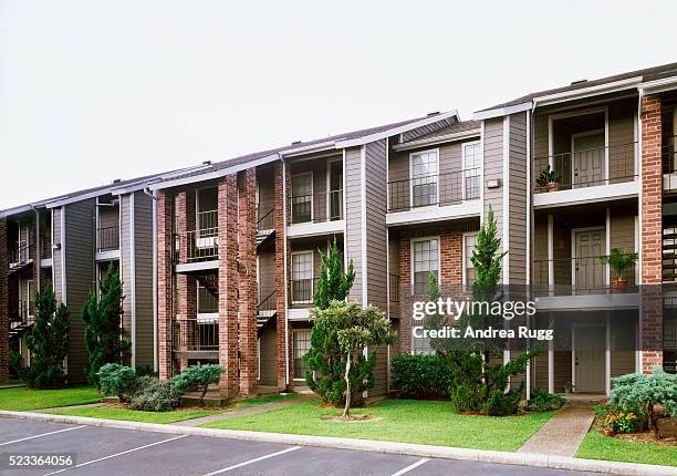 front view of brick and siding condominium buildings from parking lot - apartment foto e immagini stock