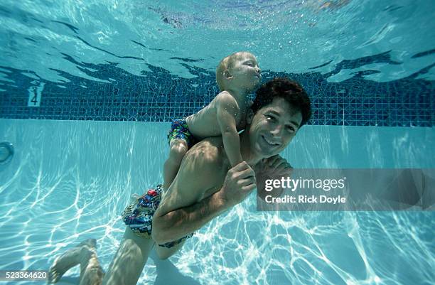 father and son swimming in pool - baby swimmer stock-fotos und bilder